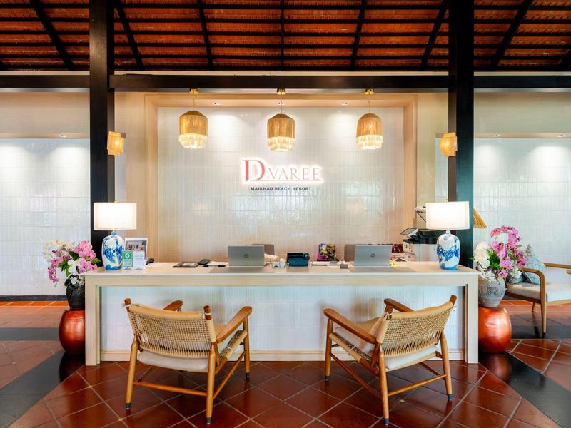 Moderne hotellobby met receptiebalie, twee stoelen en decoratieve verlichting.