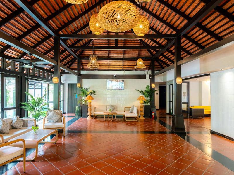 Ruimtelijke hotel lobby met houten plafond, terracottavloer, elegante zitplaatsen en warme verlichting.