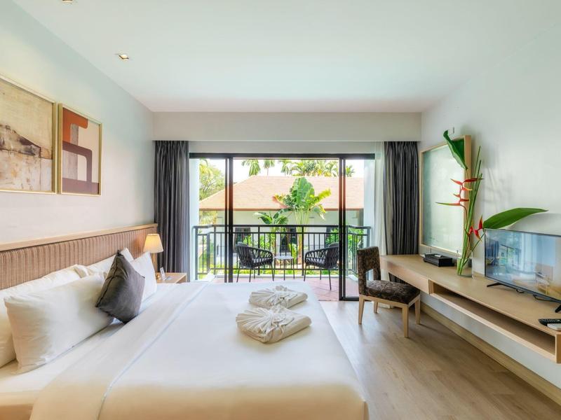 Lichte hotelkamer met tweepersoonsbed, balkon en moderne inrichting.