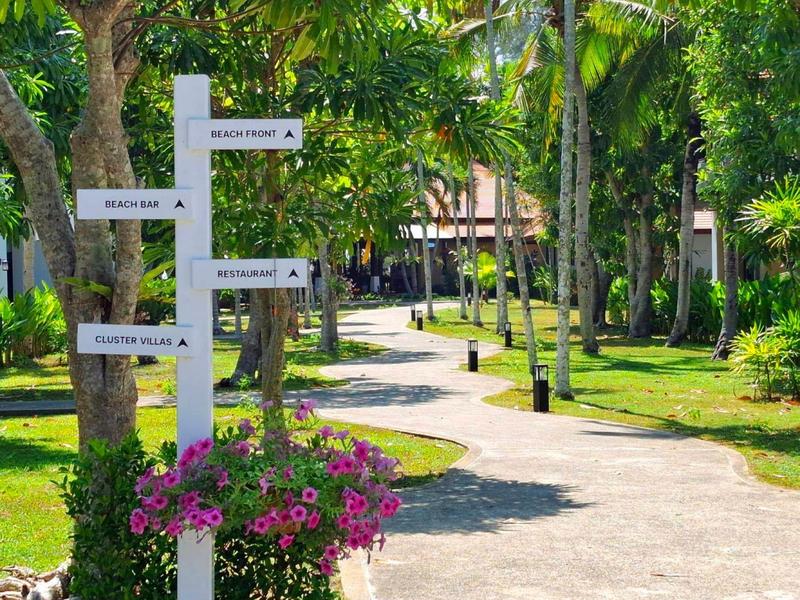 Paden door tropische tuin met bewegwijzering en bloeiende bloemen bij hotelresort