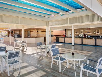 Modern outdoor area with white tables and chairs under a glass roof at a hotel