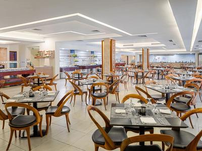 Großer, moderner Speisesaal mit vielen Holztischen und Stühlen in einem Hotel.