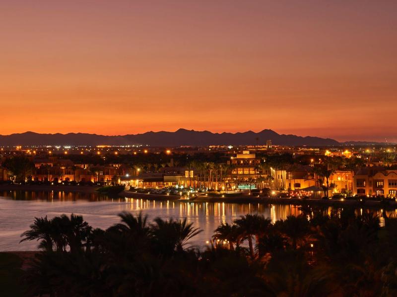 Stadt und Hafen bei Sonnenuntergang mit orangefarbenem Himmel und beleuchteten Gebäuden.