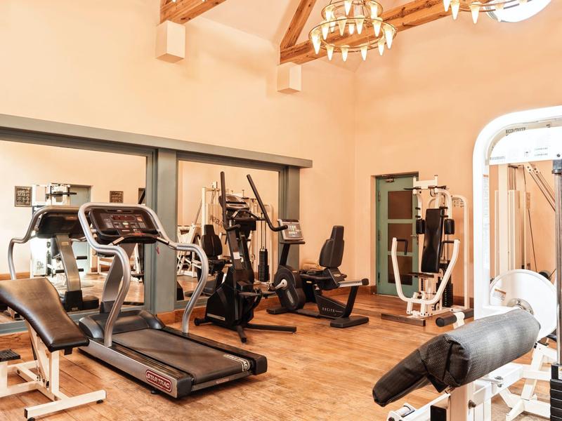 Modernes Fitnessstudio mit Laufband, Crosstrainer, Kraftmaschinen und Holzbalkendecke.