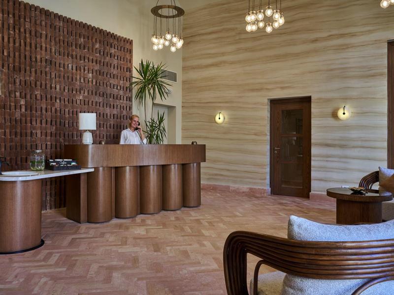 Modernes Hotellobby mit braunem Empfangstresen, Holzvertäfelung und bequemen Sitzmöbeln.