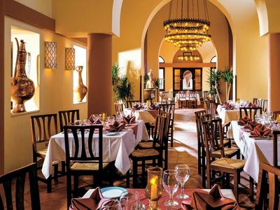 Elegantes Restaurant mit warmem Licht, dekorativen Kronleuchtern und gedeckten Tischen.