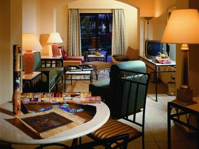 Gemütlicher Hotelzimmerbereich mit Tisch, Stühlen, Sofas und warmem Licht.