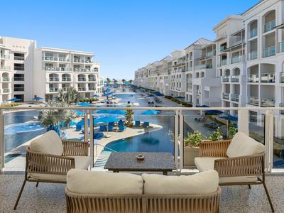 Vista dal balcone con posti a sedere su resort con piscina e più edifici sotto un cielo sereno