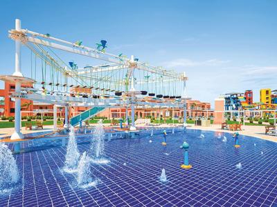 Freizeitpark mit Wasserfontänen und einem Kletterparcours über einem blauen Wasserbecken.