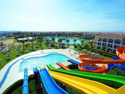 Ein großer Wasserpark mit bunten Wasserrutschen, Pools, viel Grün und einem blauen Himmel.