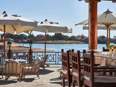 Terrazza con sedie e ombrelloni con vista su un fiume e edifici sulla riva sotto cielo sereno