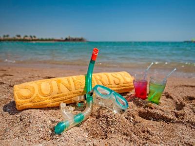 Duikbril en snorkel in het zand naast strandlaken en drankjes bij de zee