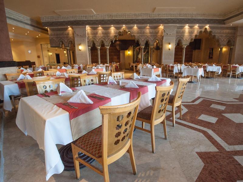 Großer Speisesaal mit weißen Tischdecken, rot braunen Servietten und hölzernen Stühlen.