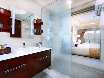 Modern hotel bathroom with wooden cabinets, double sink, and frosted glass door to bedroom.