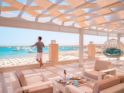 Espace extérieur moderne avec sièges confortables, fauteuil suspendu et vue sur la mer.