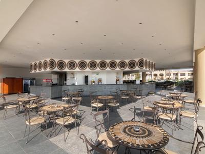 Großer, offener Restaurantbereich mit Tischen und Stühlen im Freien unter einem überdachten Bereich.