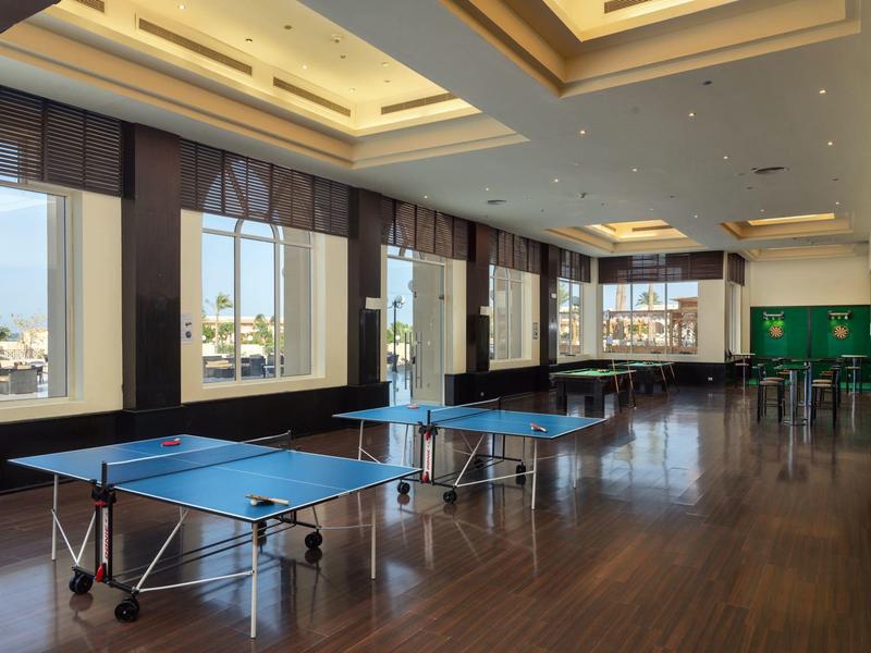 Large indoor room with several ping pong tables and big windows overlooking a cityscape.