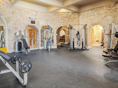 Salle de sport lumineuse avec murs en pierre et équipements variés.