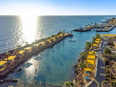 Sunset over a harbor with yellow umbrellas and marina facilities.