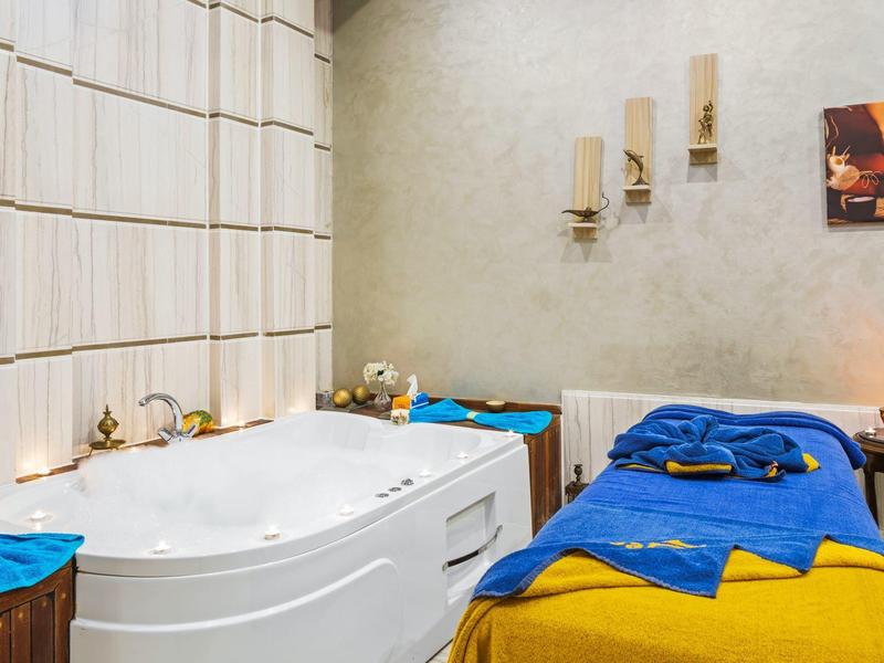 Relaxation room with whirlpool bathtub, lounge bed, soothing lighting, and wall decor.