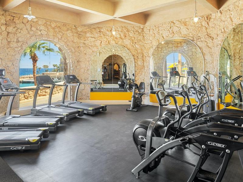 Gym with treadmills, exercise machines, and windows showing ocean views.