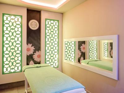 Jasny pokój spa z łóżkiem do masażu i dekoracyjnymi panelami ściennymi z kwiatowymi wzorami.