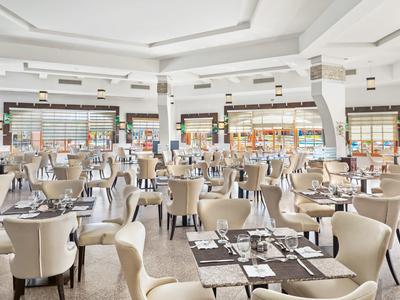 Jasna, przestronna restauracja z beżowymi krzesłami i zastawionymi stołami.