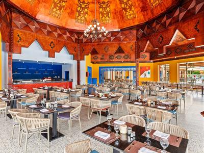 Jasna, kolorowa restauracja z tradycyjnym sufitem i nowoczesnymi miejscami do siedzenia.