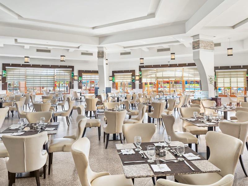 Jasna, przestronna restauracja z beżowymi krzesłami i zastawionymi stołami.