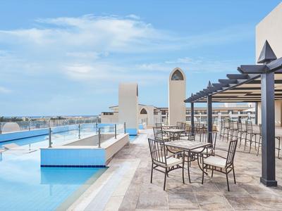 Dachterrasse mit Pool, Sitzbereich und Blick auf die Stadt unter blauem Himmel