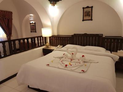 A cozy double bed with white linens and decorative towels in a hotel room.