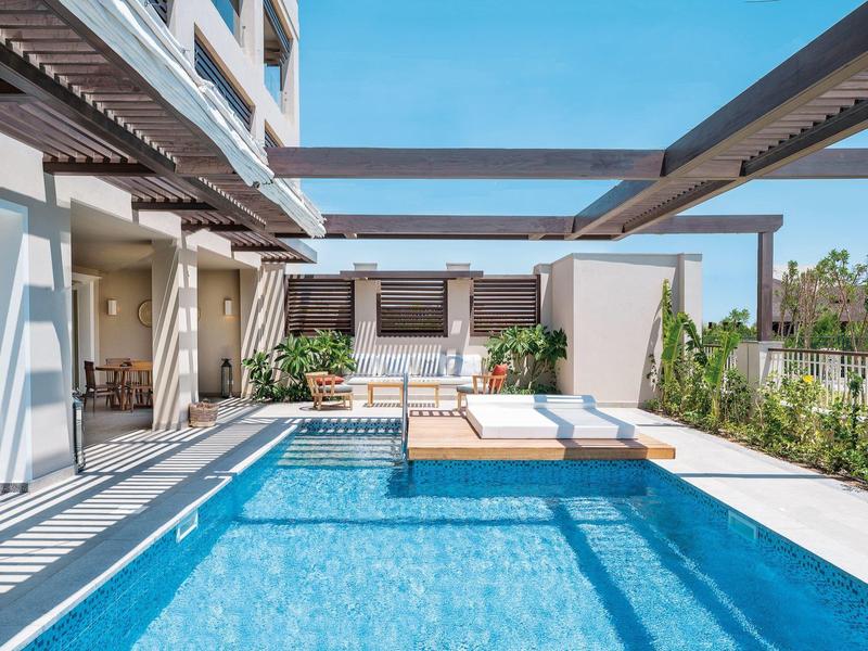 Modern outdoor pool with lounge area and seating on a sunny day.