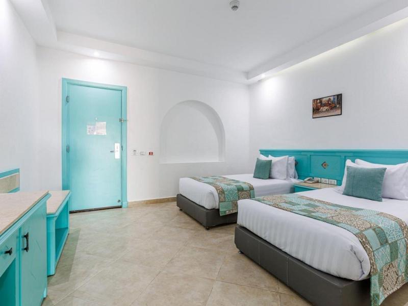 Modern hotel room with two beds, turquoise accents, and minimalist design.