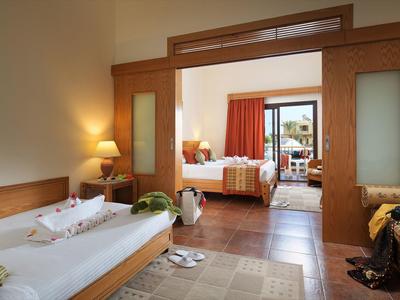 Gemütliches Hotelzimmer mit Einzelbett, Sofa, Tischlampe und Zugang zu Schlafzimmer sowie Balkon.