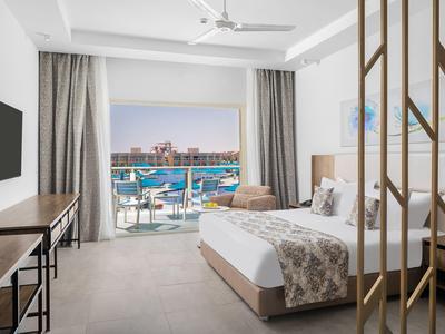 Lichte hotelkamer met kingsize bed, balkon met uitzicht op zwembad en zee.