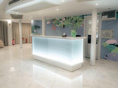 Modern hotel reception desk with glowing light and floral wall mural in bright, clean lobby.