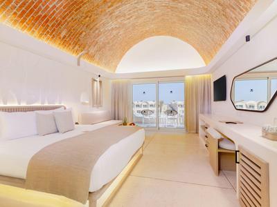 Helles, modernes Schlafzimmer mit gewölbter Decke, großem Bett, Spiegel und Balkon mit Blick nach draußen.