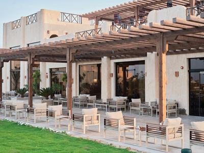 Area esterna con tavoli, sedie e pergolato in una terrazza di un hotel moderno.