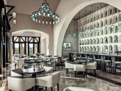 Elegant hotel dining area with arched windows, modern chairs, and a large chandelier.