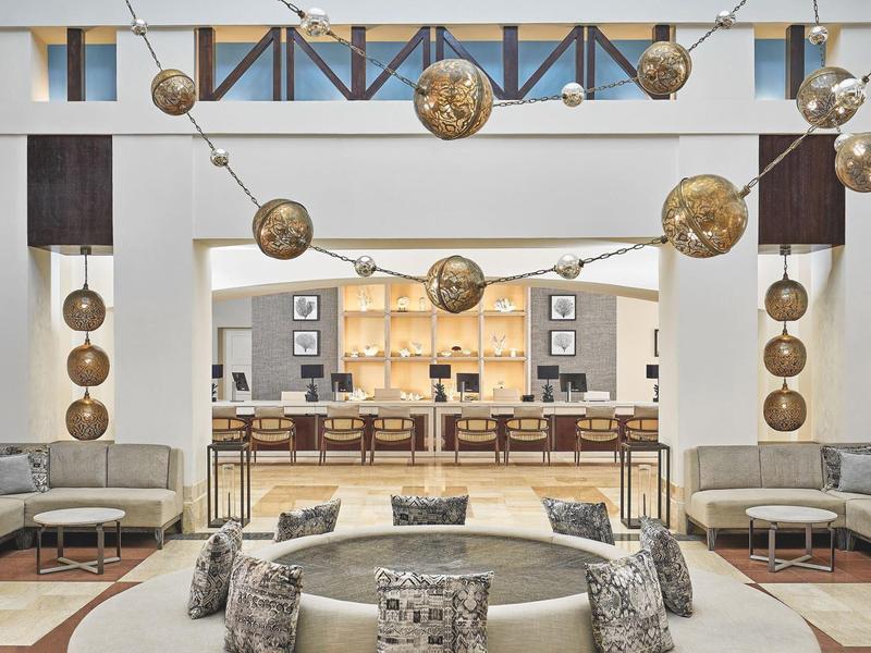 Modern hotel lounge with circular seating and hanging globe lights in the reception area.