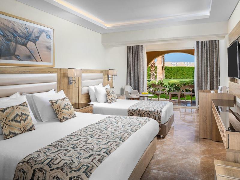 Modern ingerichte hotelkamer met twee bedden en balkon met uitzicht op zee.