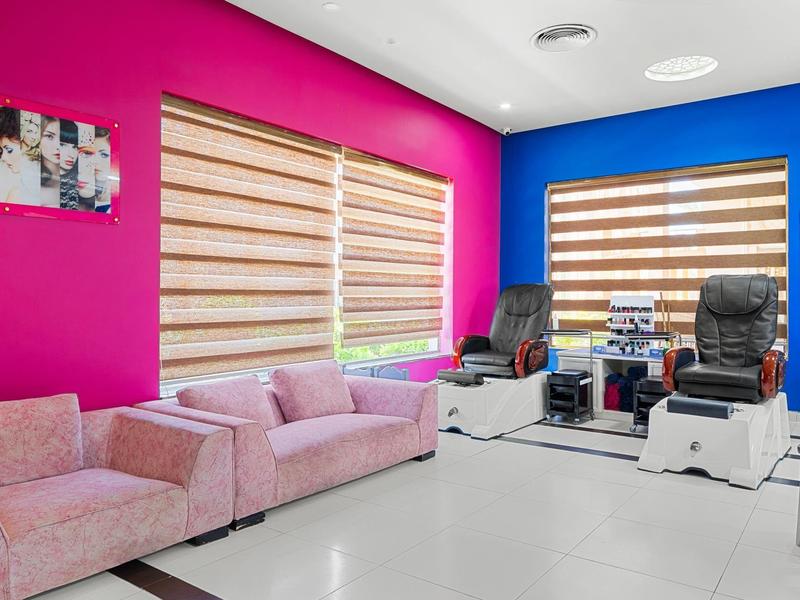 Sala moderna de bienestar con pared rosa, sillones cómodos y sillas de masaje.