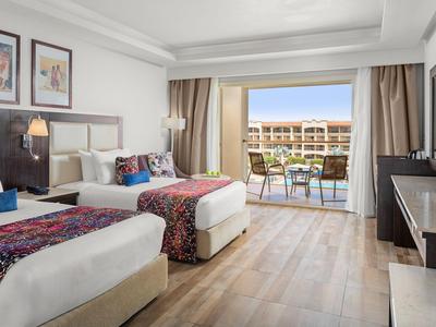 Hotel room with two single beds, wooden floor, and balcony overlooking courtyard.