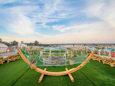 Deck chairs on green grass overlooking a river under a blue sky with clouds.