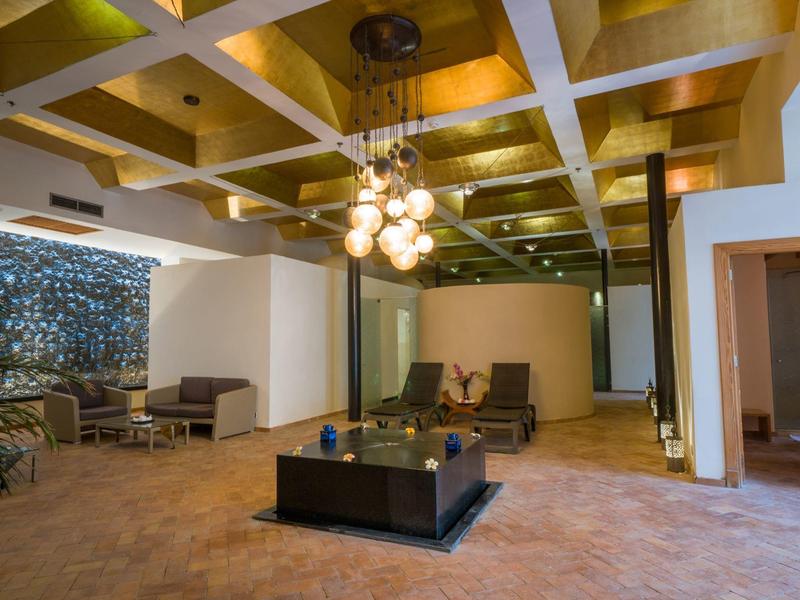 Hotel lounge with modern chandelier, comfortable seating, and polished tiled floor under a coffered ceiling.