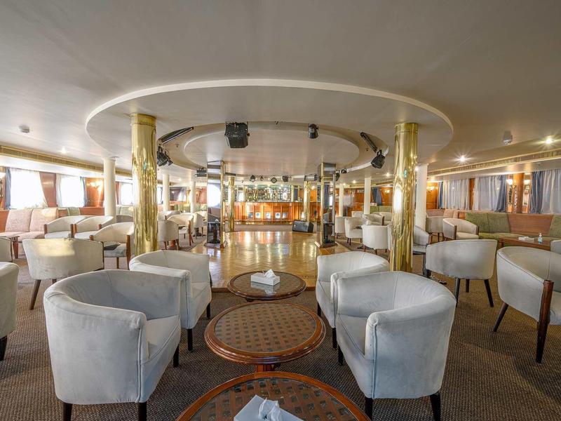 Prostorný salón s bílými křesly a zdobenou podlahou v elegantním osvětleném prostoru.