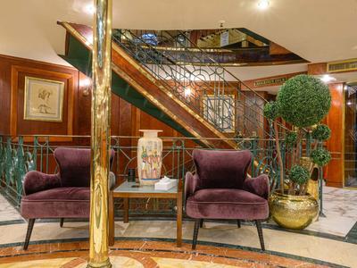 Lobby d'hôtel élégante avec deux fauteuils violets, vase sur la table et ascenseur en arrière-plan