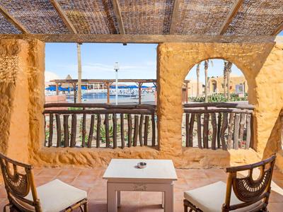Cozy outdoor seating area with rustic wooden chairs and a table, overlooking a marina.