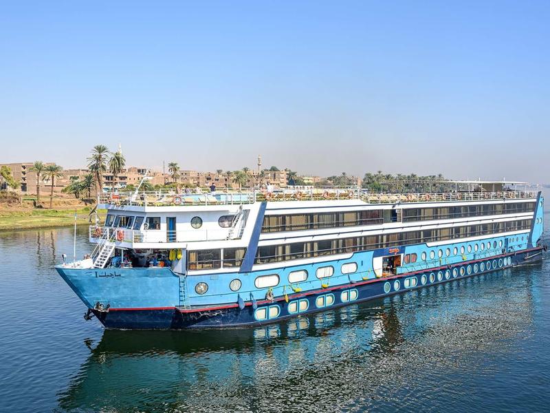 Bateau bleu naviguant sur une rivière calme près d'une ville au bord de l'eau.