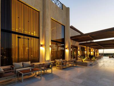 Área exterior moderna de un hotel con asientos y luz cálida al atardecer.